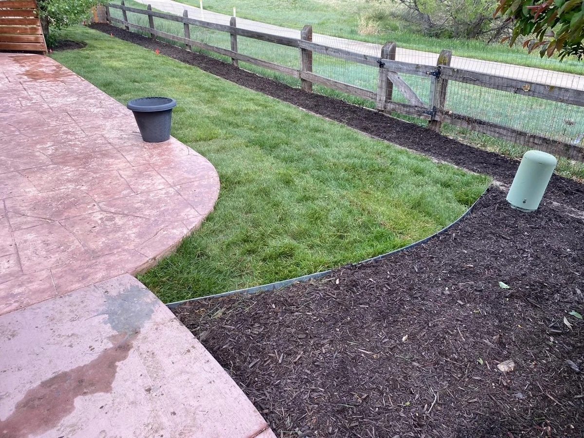Lawn and mulched beds beside a curved patio in an Outdoor Legacy owner-uploaded photo